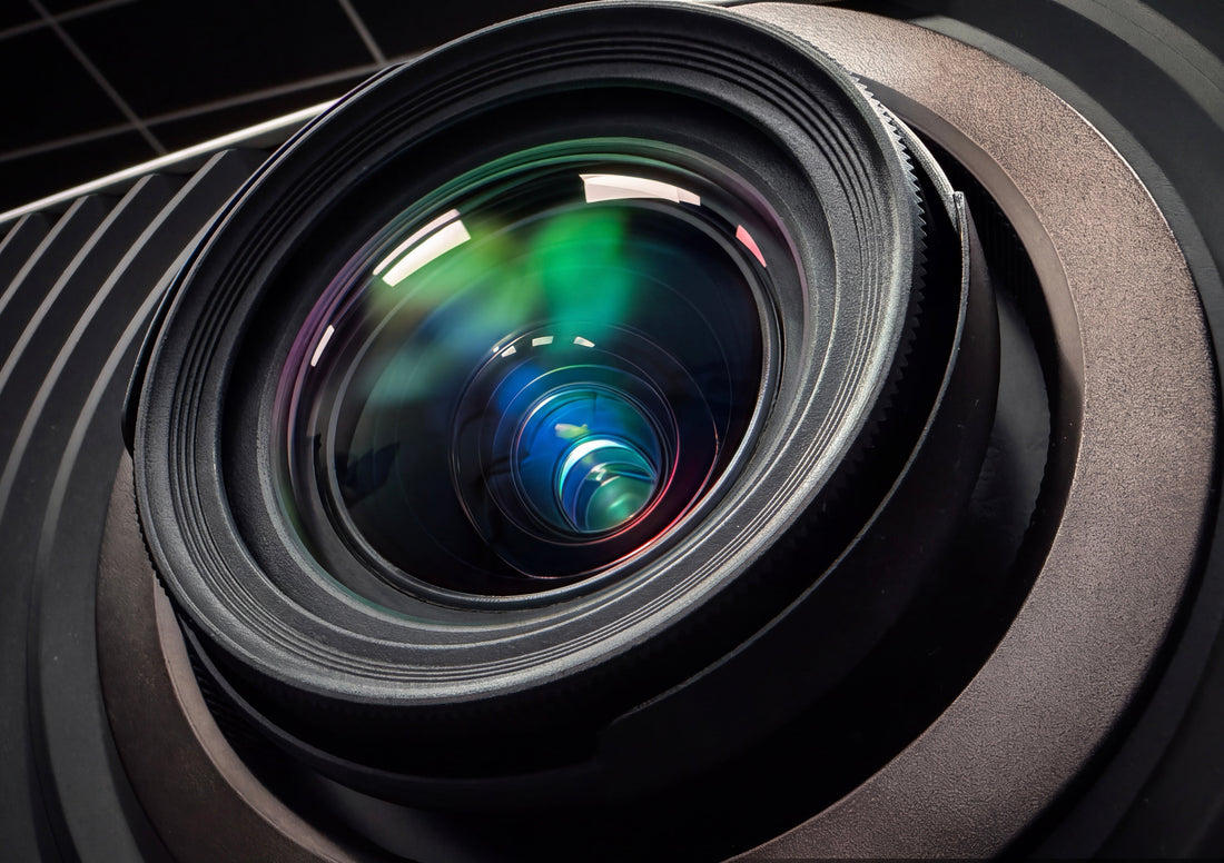 Close-up of a projector lens with blue and green reflections.