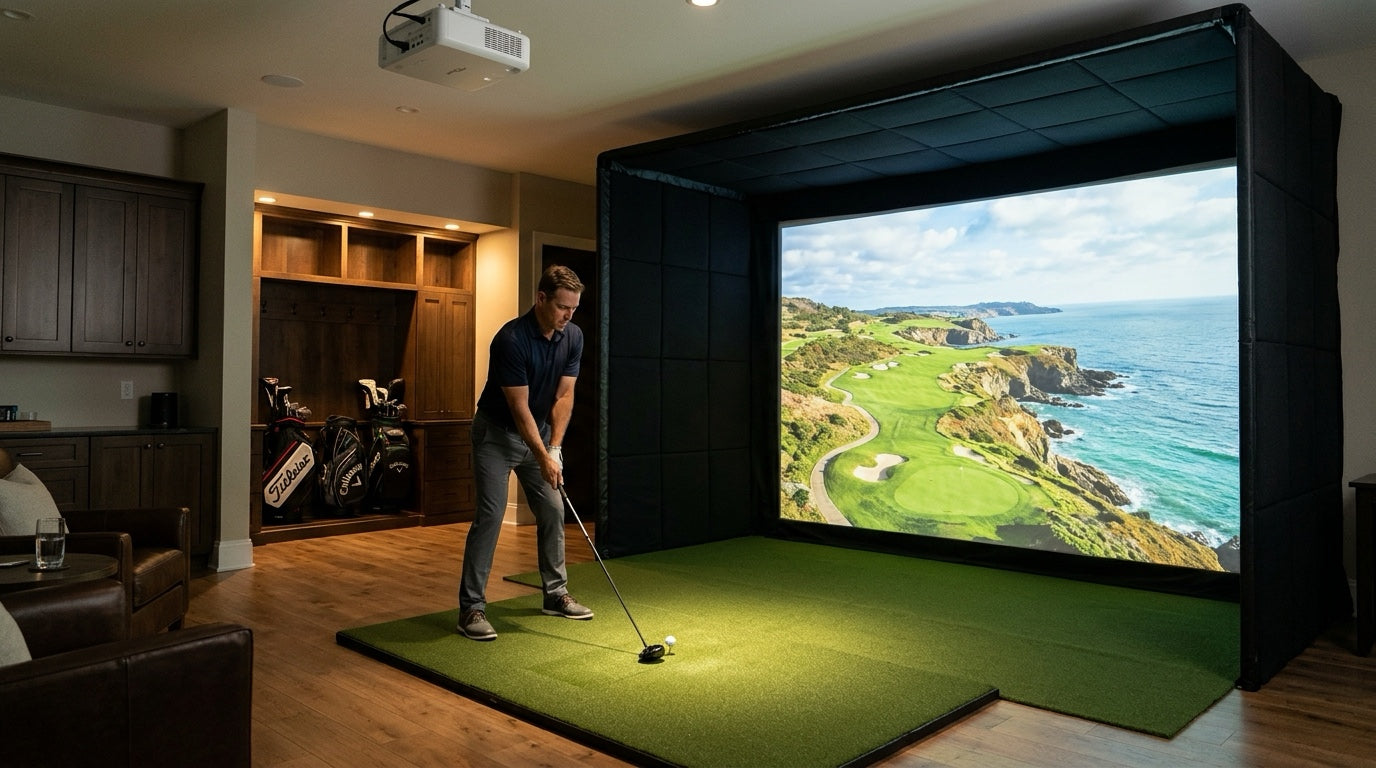 Home golf simulator bay with a ceiling-mounted white short-throw laser projector illuminating a woven impact screen while overhead spotlights illuminate the hitting mat